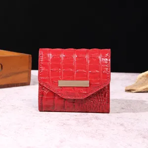 Vista detallada de una cartera vintage roja para mujer con grabado de cocodrilo.