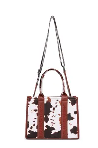 Detalle de un bolso tote con estampado de vaca y adornos de cuero marrón