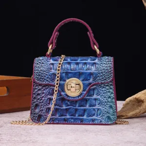 Close-up of a blue crocodile embossed leather handbag with magenta trim and gold hardware