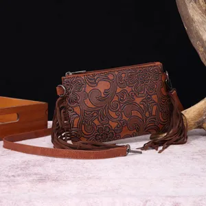 Detalle de bolso bandolera vintage estilo bohemio en cuero marrón grabado con flecos