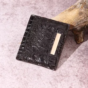 Primo piano di un porta carte marrone scuro con trama a coccodrillo e dettaglio oro.