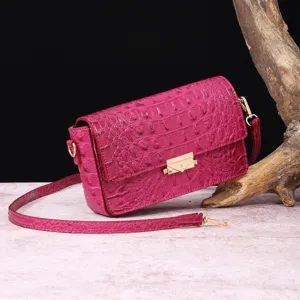Bolso bandolera vintage fucsia grabado en cocodrilo con cierre de sobre dorado y correa.