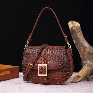 Vista detallada del bolso de hombro marrón con diseño de cocodrilo y hebilla dorada