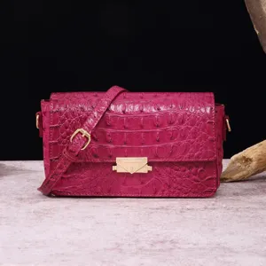 Primer plano detallado de bolso bandolera en cuero grabado cocodrilo magenta y metal oro