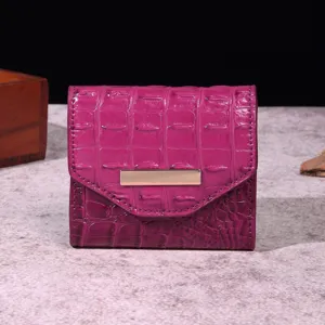 Vista detallada de la billetera trifold de cocodrilo magenta con barra dorada