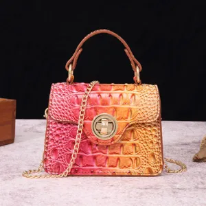 Close-up of retro crocodile embossed leather handbag with gradient pink and orange finish