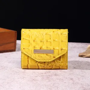 Detalle de una cartera para mujer en color amarillo brillante con relieve de cocodrilo.