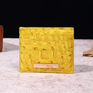 Dettaglio di un porta carte vintage giallo con motivo coccodrillo e accenti metallici.