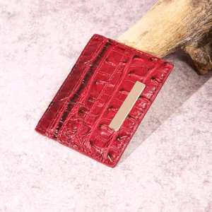 Dettaglio di un porta carte in pelle rossa con motivo coccodrillo e barra dorata