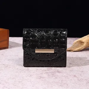 Detalle de una cartera vintage negra con estampado de cocodrilo y herrajes dorados