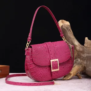 Vista detallada del bolso magenta con patrón de cocodrilo y elegante hebilla dorada.
