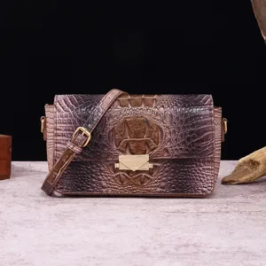 Vista detallada de bolso bandolera de cuero grabado cocodrilo con cierre dorado