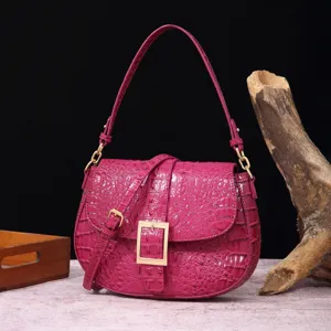 Vista detallada del bolso de hombro vintage fucsia con patrón de cocodrilo y hebilla.