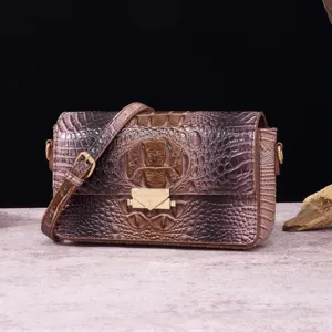 Primer plano de bolso bandolera vintage para mujer con estampado de cocodrilo marrón y herrajes