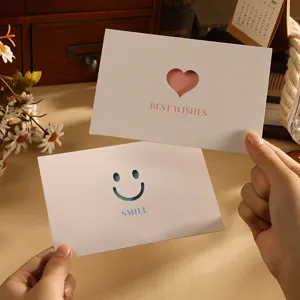 Detailansicht minimalistischer weißer Grußkarten mit Herz- und Smiley-Ausschnitt-Designs.