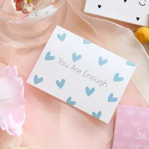 Close-up of minimalist greeting card featuring blue hearts and 'You Are Enough' message.