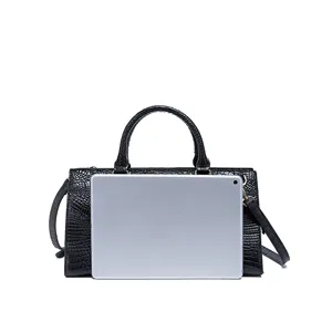 Bolso de mano negro vintage grabado cocodrilo comparado con tableta por tamaño