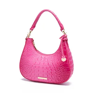 Vista dettagliata della borsa a spalla rosa con trama a coccodrillo e dettagli dorati.