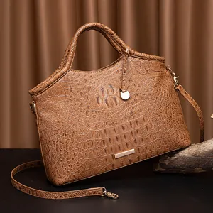 Detalle del bolso de mano marrón con textura de cocodrilo y adornos metálicos retro