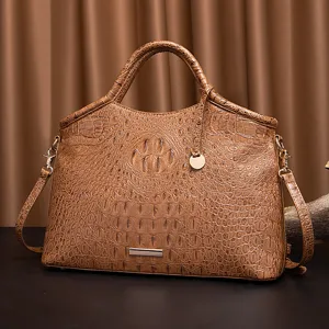 Vista frontal de un bolso marrón con grabado de cocodrilo y toques dorados