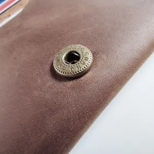 Macro detail of the brass snap button on a retro crazy horse leather card holder