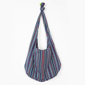 Primer plano de un bolso hobo étnico azteca vintage colgado en un gancho de pared blanco