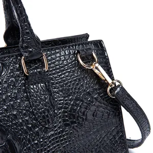 Detalle de un bolso negro en cuero grabado de cocodrilo con herrajes de metal dorado