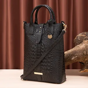 Detalle de bolso negro con relieve de cocodrilo y elegantes herrajes dorados