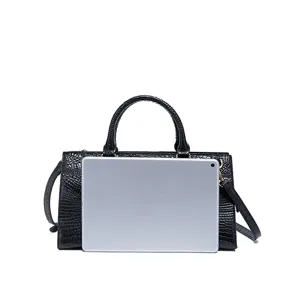Bolso de mano negro con relieve de cocodrilo comparación de tamaño con tableta plata