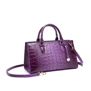 Vista detallada de un bolso de mano morado con relieve de cocodrilo y herrajes dorados