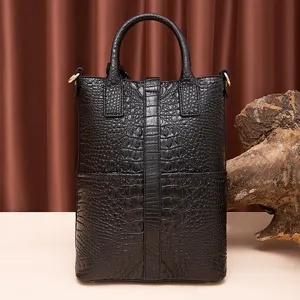 Vista frontal de bolso vintage negro con patrón de cocodrilo y asas superiores firmes