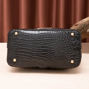 Vista inferior de bolso vintage negro con patrón de cocodrilo y clavos