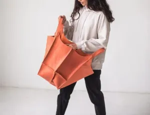 Modelo posando con un gran bolso tote naranja vintage de piel suave encerada al aceite.