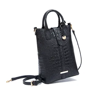 Detalle de bolso negro con relieve de cocodrilo, hebilla dorata y correa fina