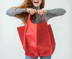 Modelo que sostiene un gran bolso de cuero rojo para demostrar su escala sobredimensionada