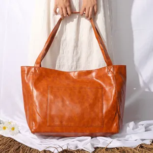 Bolso tote grande de cuero encerado marrón con bolsillo frontal en un entorno rústico