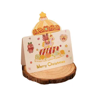 Festive Christmas greeting card featuring gold foil reindeer carousel on a rustic wood base