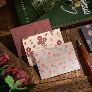 Detalle de tarjetas de felicitación florales vintage con letras doradas en una mesa