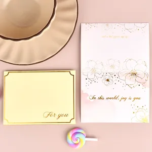 Primer plano de tarjetas de felicitación doradas con flores y texto For You