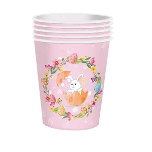 Vue détaillée de gobelets en papier de Pâques roses avec motif de lapin et couronne florale.