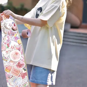 Primer plano de pegatinas 3D rosas en un monopatín sostenido por una chica al sol.