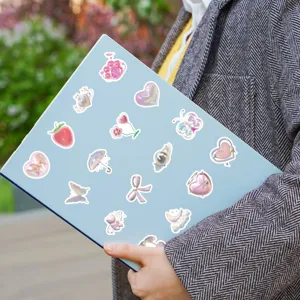 Detalle de pegatinas rosas 3D iridiscentes aplicadas en la tapa de un portátil azul