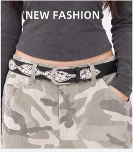 Detail view of a black Y2K style studded belt with a silver needle buckle on camo pants.