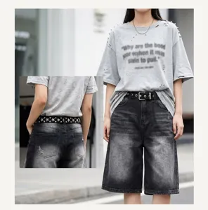 Detailed view of a heavy-duty studded black belt styled with washed denim shorts on a model