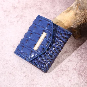 Primer plano de cartera de mujer azul con relieve de cocodrilo y detalle dorado