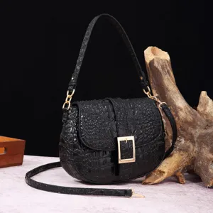 Elegante bolso bandolera negro con relieve de cocodrilo y hebilla dorada, detalle.