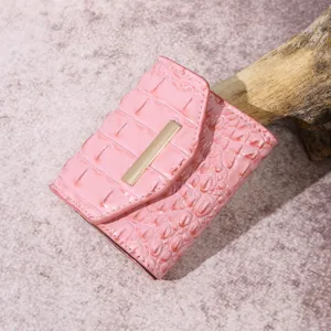 Primer plano de una elegante cartera rosa con textura de cocodrilo y barra oro