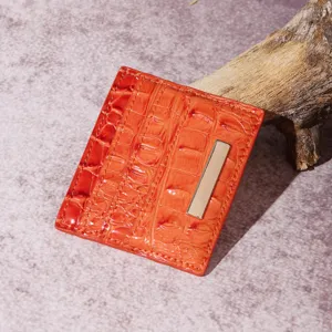 Dettaglio macro di un porta carte arancione con motivo coccodrillo e barra in metallo dorato
