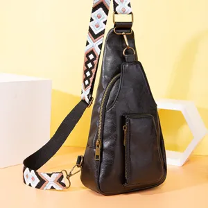 Detalle de la correa ancha de jacquard bohemio en un bolso bandolera de cuero negro.