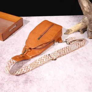 Primer plano de un bolso bandolera retro marrón con correa ancha de estilo bohemio.